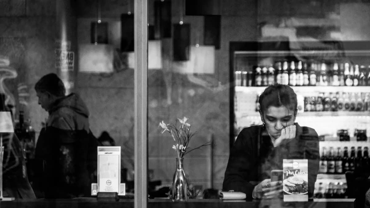 frau schaut nachdenklich aufs handy im café