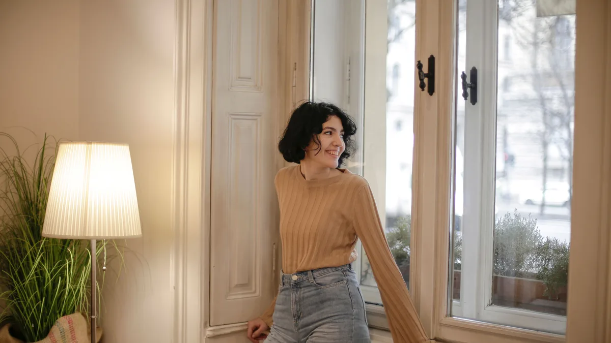 frau allein am fenster lächelnd