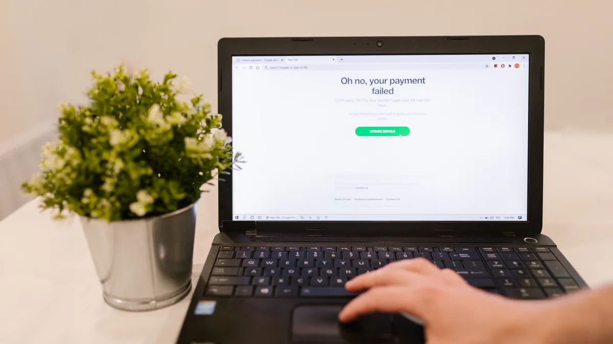 Person sitzt am Laptop, auf dem Bildschirm erscheint eine Zahlungsmeldung